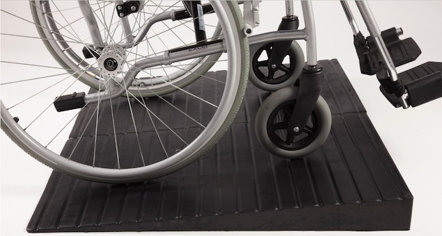 Manual wheelchair going up rubber threshold ramp 