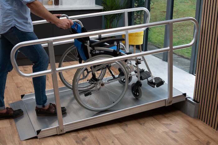 Wheelchair Ramp with handrails with a wheelchair going up the ramp to overcome a step 