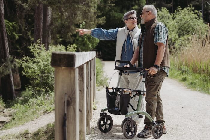 Man and lady walking in countryside, man using a green  Saljol Allround Rollator