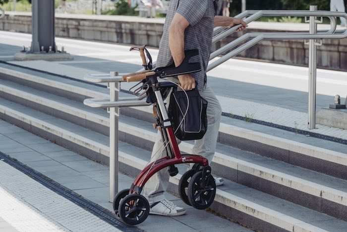 Folded red rollator being lifted up stairs 