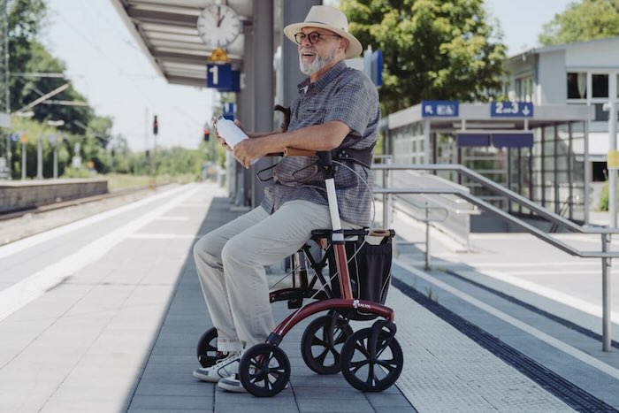Man sat at train station on red  Saljol Allround Rollator