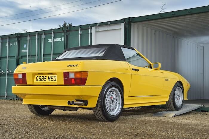 Yellow car driving up a pair of aluminium car ramps into a container