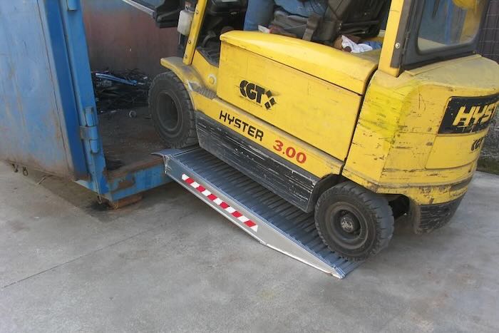 Forklift driving up aluminium ramp into a container