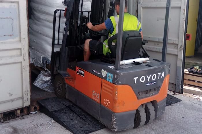 Forklift driving up rubber container ramp