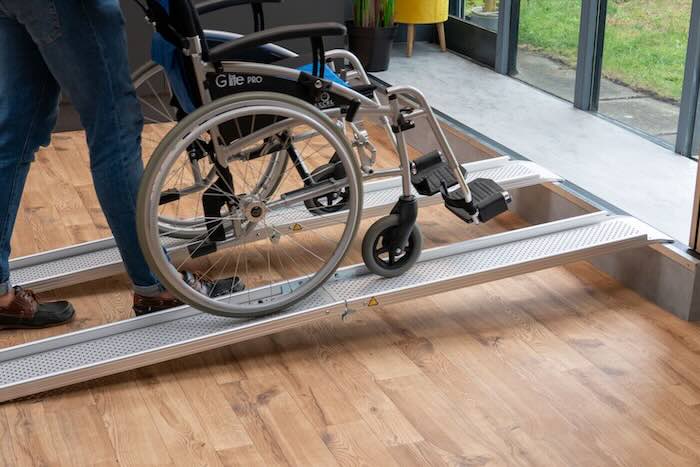 Wheelchair being pushed up a pair of ramps Wheelchair being pushed up a pair of ramps