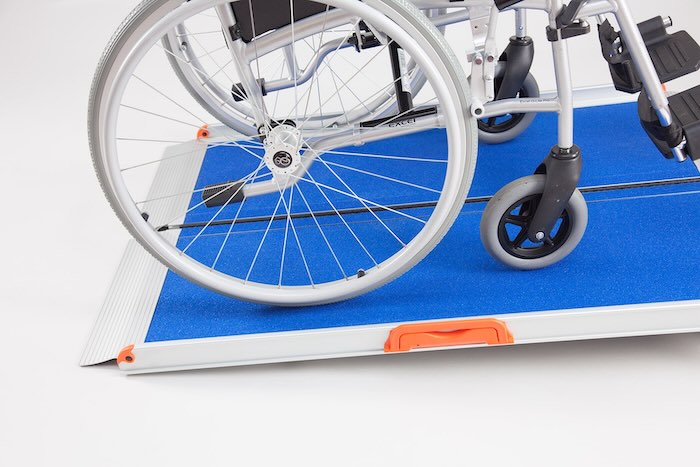Blue wheelchair ramp with wheelchair going up ramp