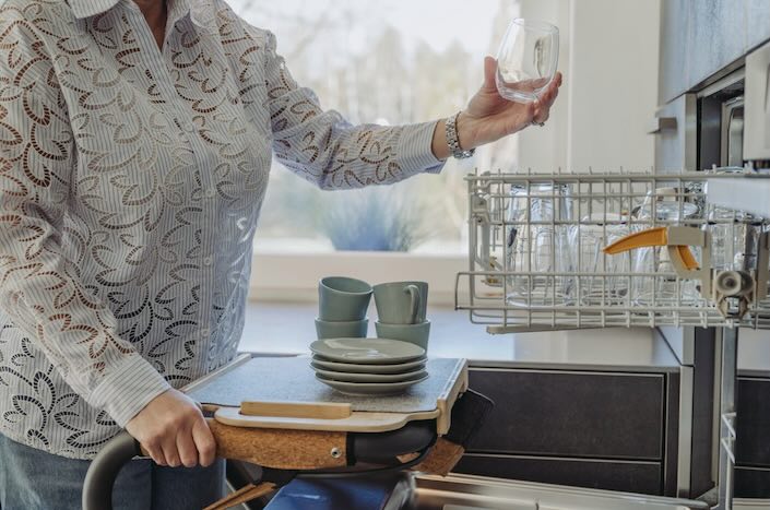 Lady using Saljol Indoor Rollator in home Lady loading dishwasher in kitchen using Saljol rollator