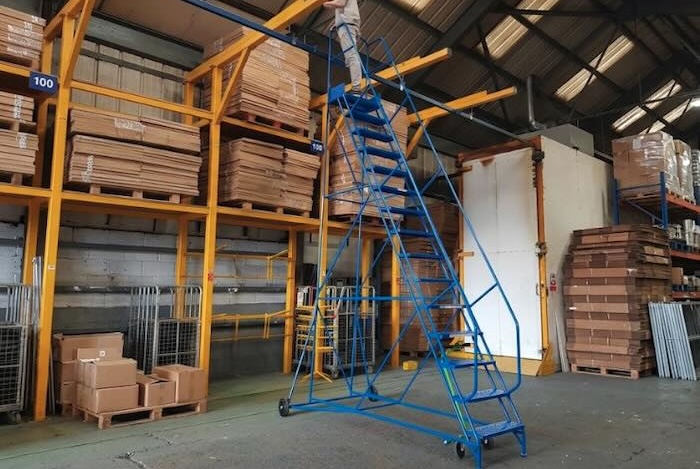 Mobile ladder in use in warehouse with a person stood on the ladder picking items