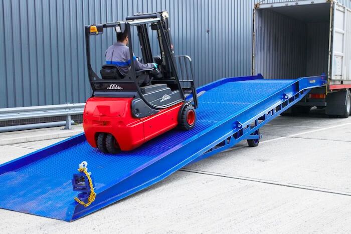 Forklift driving up yard ramp into a container