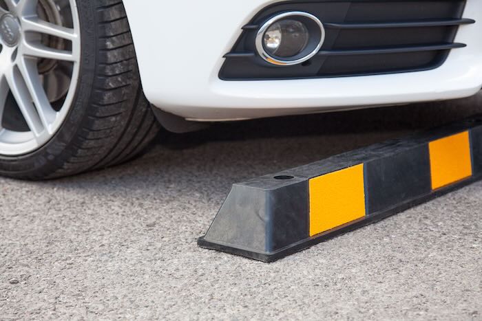 Car infront of rubber wheel stop on concrete 