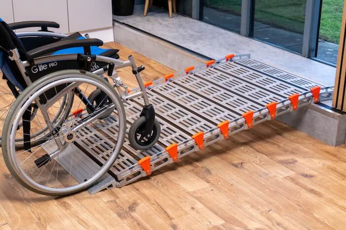 Wheelchair going up rollable ramp onto step
