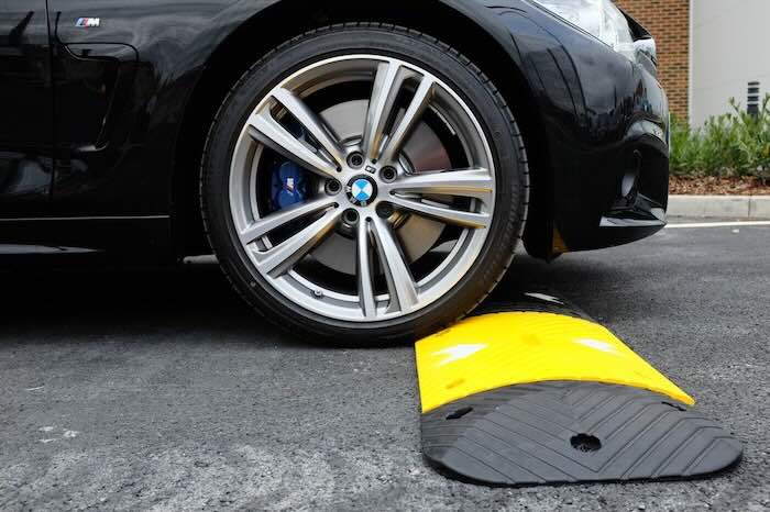 Car driving over rubber speed bump on tarmac road