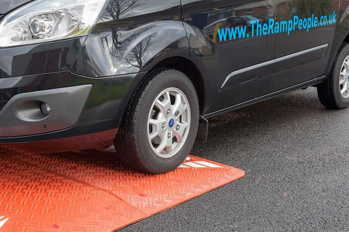 Van driving over red speed cushion 