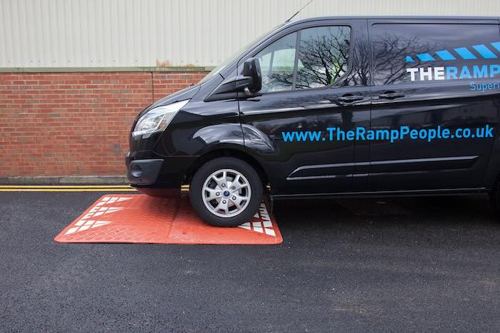 Van driving over red speed cushion 