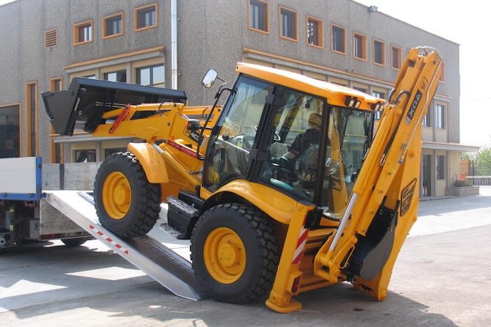 JCB driving up pair of aluminium loading ramps 