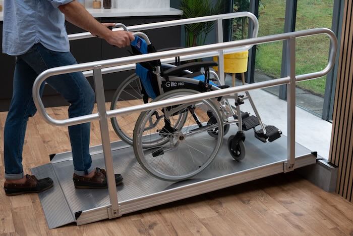 Wheelchair going up a ramp with dual handrails